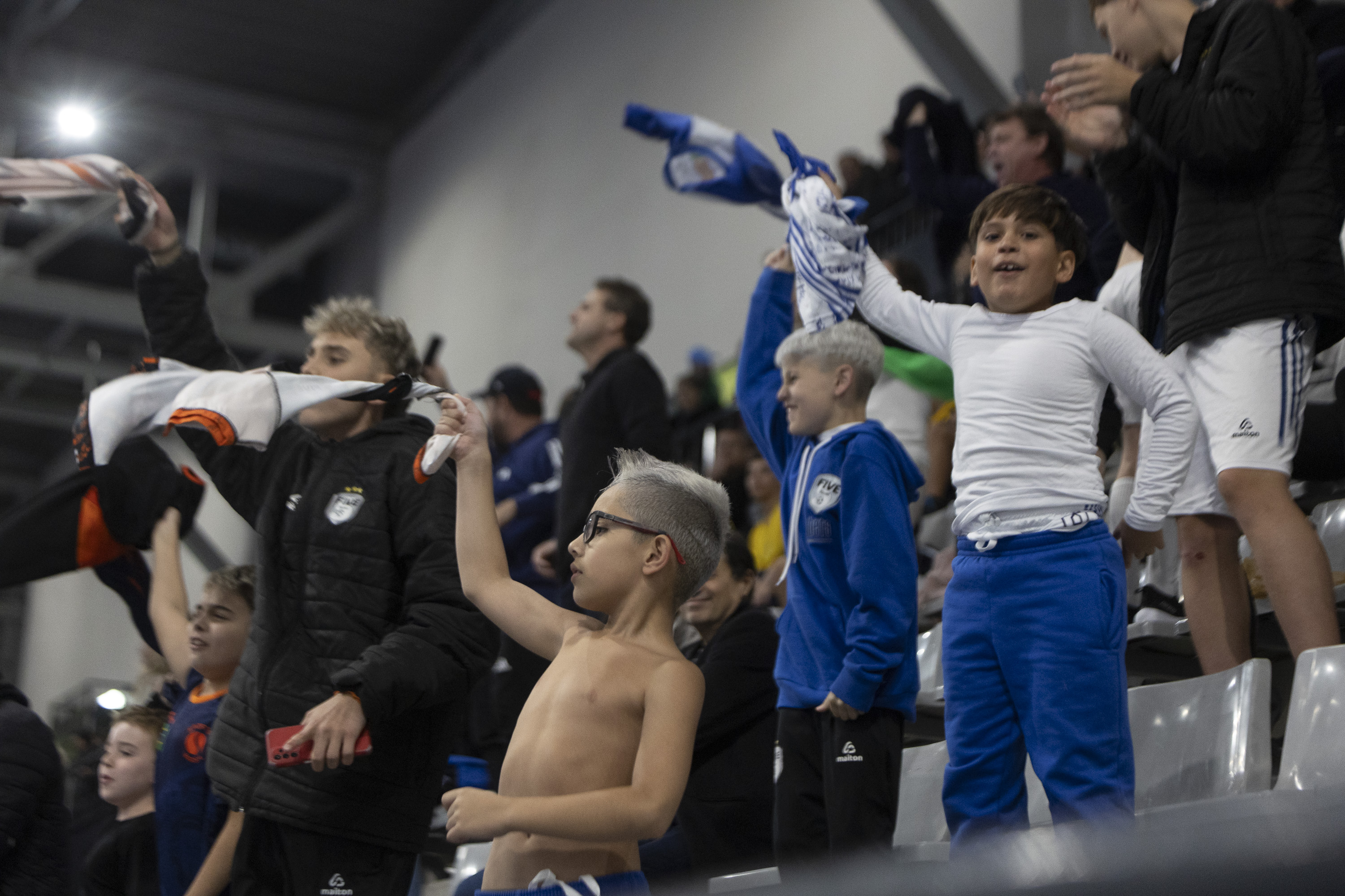 Young fans celebrating in the stands at a United Futsal event